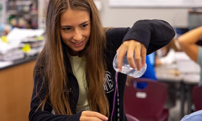 A girl pours water down a string